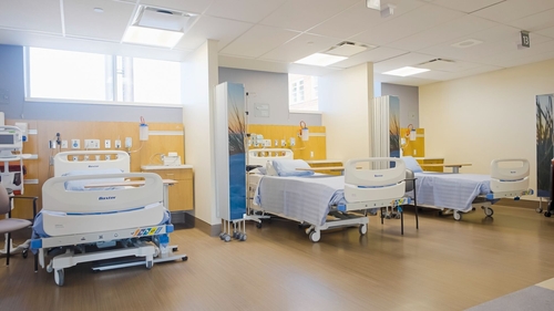 A bright and modern bed bay in the Cancer & Medical Care Clinic, featuring several patient beds separated by privacy curtains. The space is filled with natural light and equipped with essential medical tools, designed to support comfort and care during treatment.